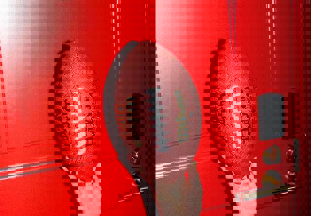 Someone holding up an American football against the iconic Virgin Hotel's red hotel room doors.