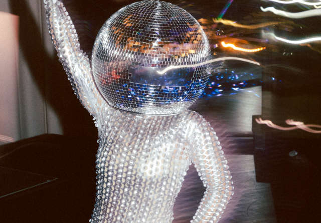 Performer wearing a dazzling disco ball helmet and sparkling outfit at a lively party at Virgin Hotels.