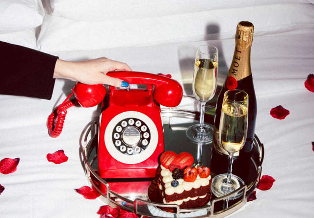 Tray of refreshments and stylish phone on bedding at Virgin Hotels Dallas.