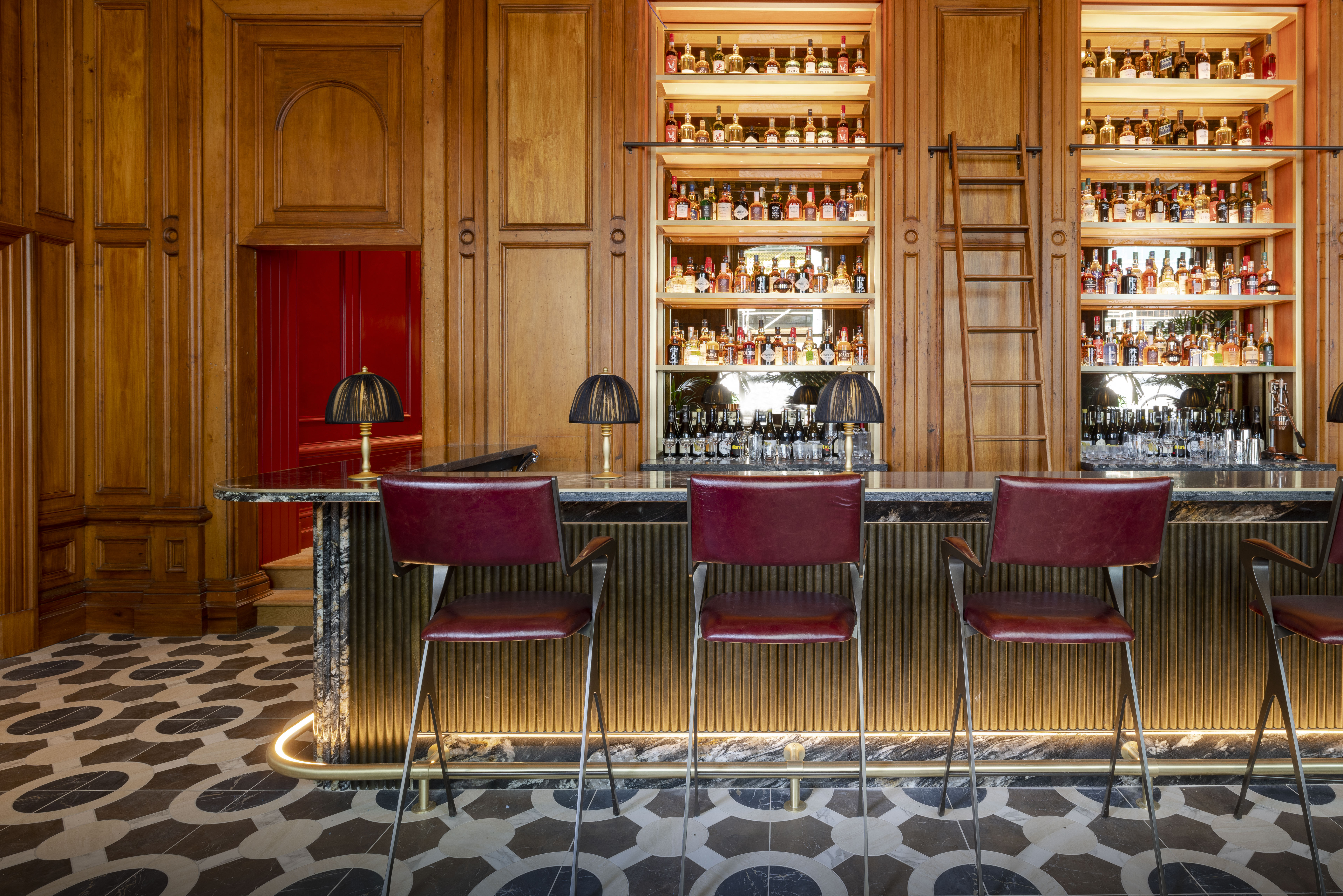 Stylish bar at Virgin Hotels Edinburgh with sleek stools, dim lighting, and a stocked bar for an inviting atmosphere.